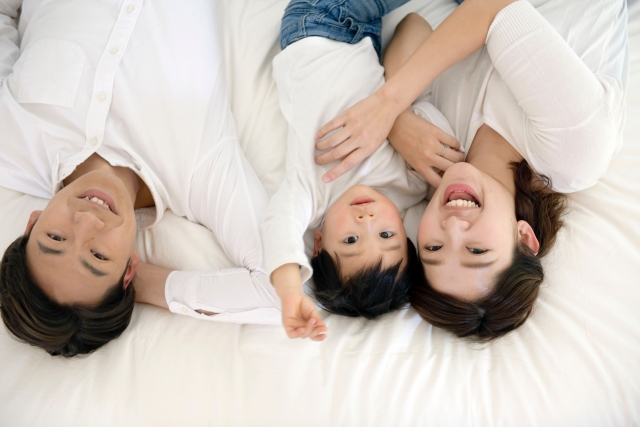 マットレスに横たわる親子３人