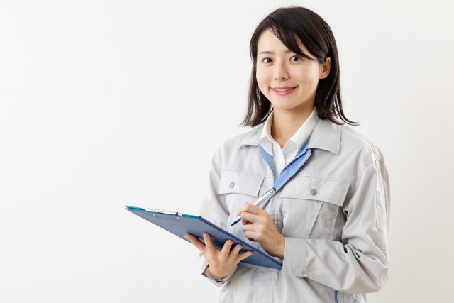 作業ジャンバーを着た若い女性がバインダーを持ってチェックしている