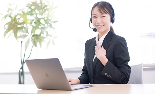 ノートパソコンを見ながらヘッドホンを付けて対応している女性