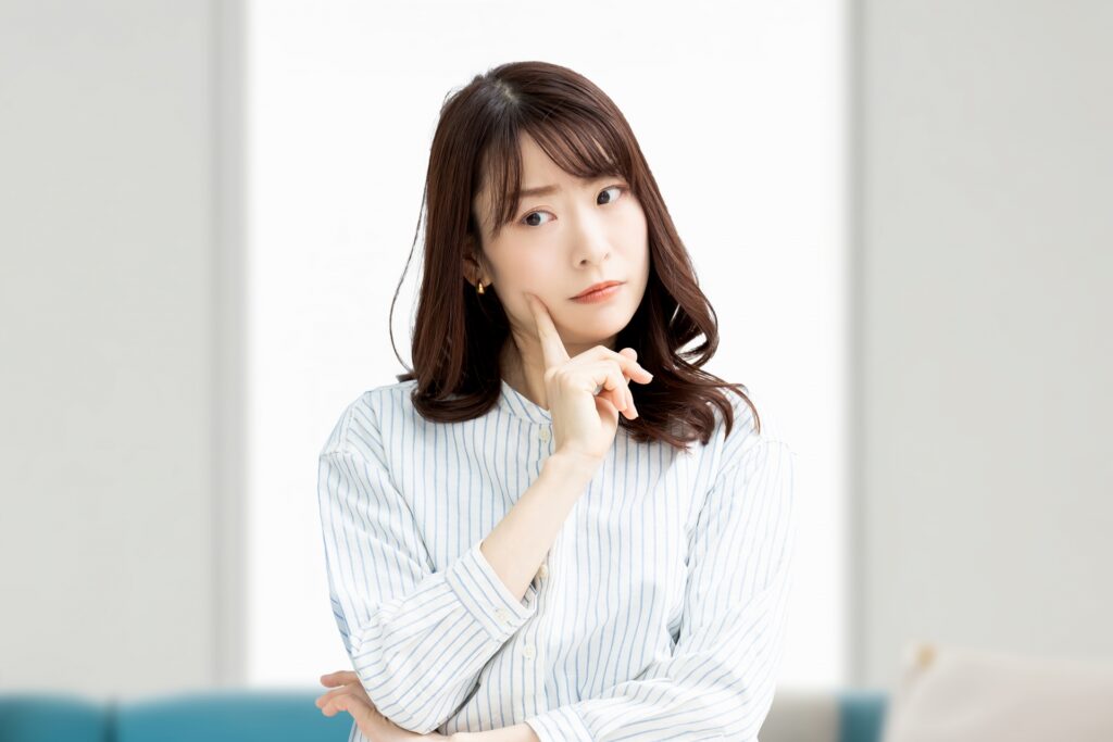 右の頬に人差し指をあてて考え事をしている女性