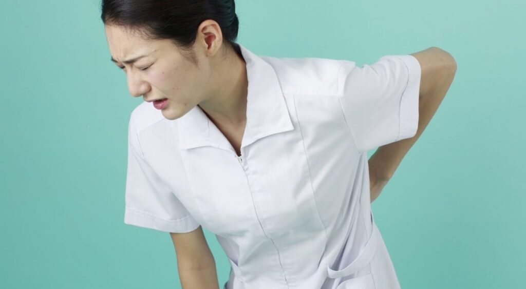 腰痛で腰に手を当てて痛い表情の女性