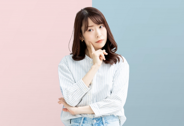 若い女性が頬に人差し指を頬にあてて考え事をしていえる。