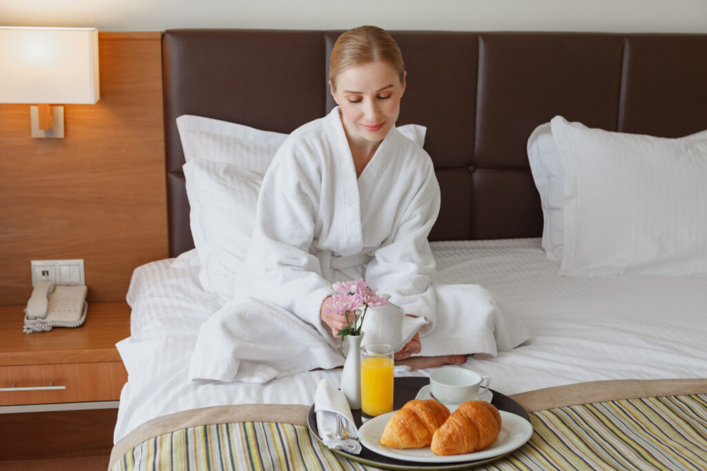ホテルのベッドの上で食事をしている女性